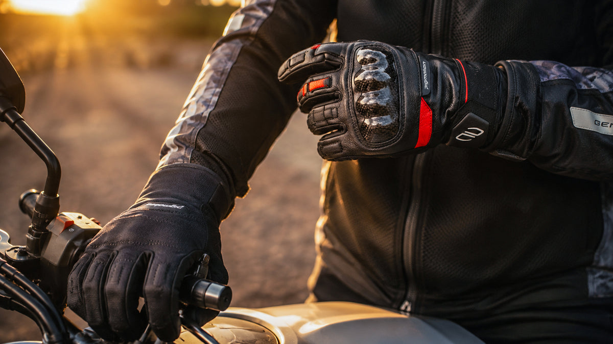 Guantes de moto Pigmalion en cuero y textil con protección de nudillos, sobre una moto al atardecer